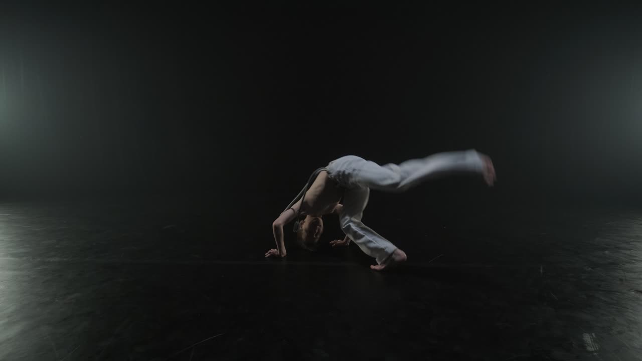 Lottatori di Capoeira che eseguono mosse dinamiche sul palco. Arti marziali, danza e acrobazie in azione. Atleti a torso nudo che mostrano forza, flessibilità e tecnica sotto i riflettori