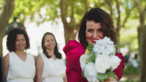 retrato de hermosa dama de honor con ramo de novia mirando a la cámara y sonriendo