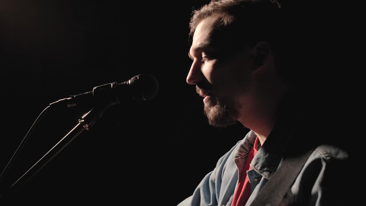 un músico está tocando la guitarra en un gran escenario con miembros de la audiencia sosteniendo linternas en el fondo. el auditorio está lleno de hermosas luces parpadeantes.