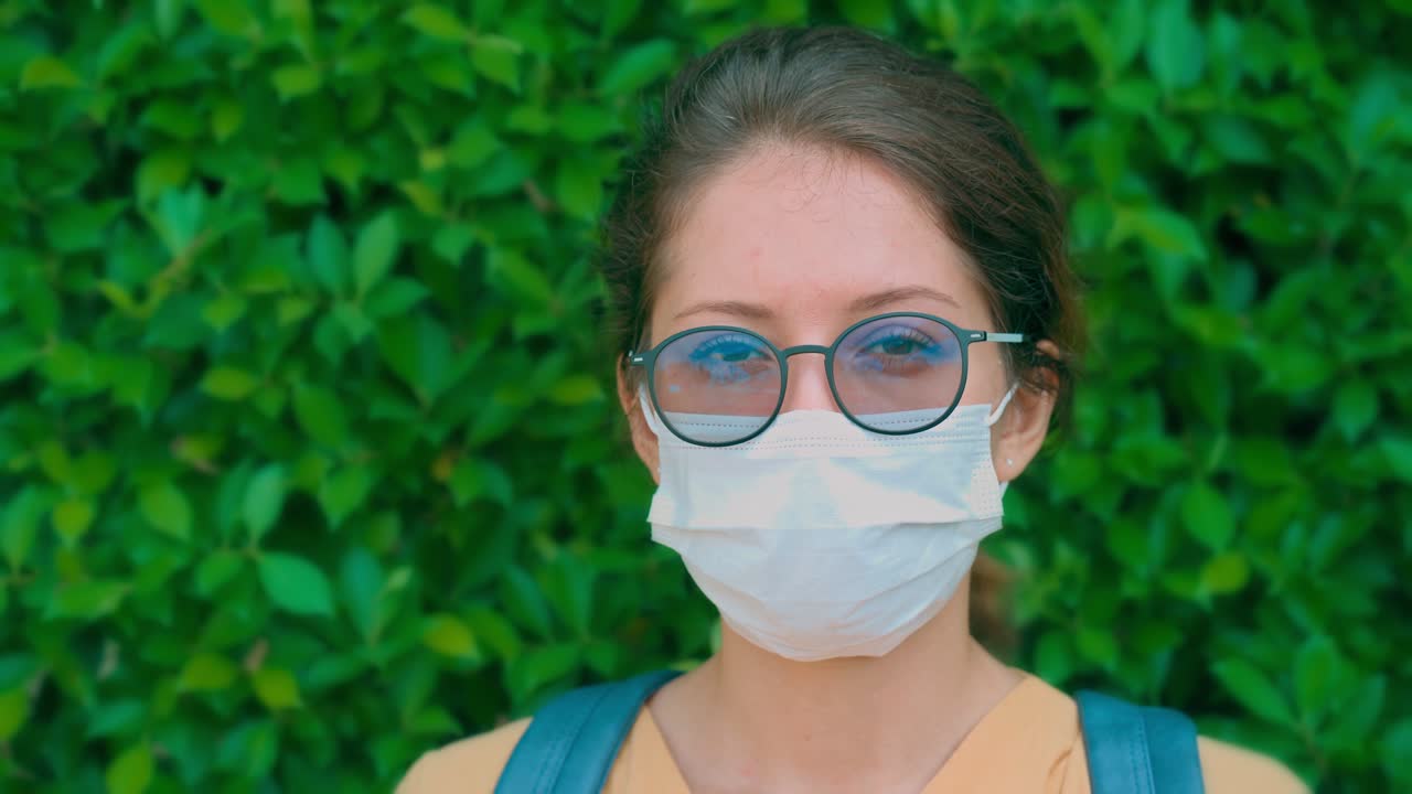 Giovane donna che indossa mascherina e occhiali su sfondo verde