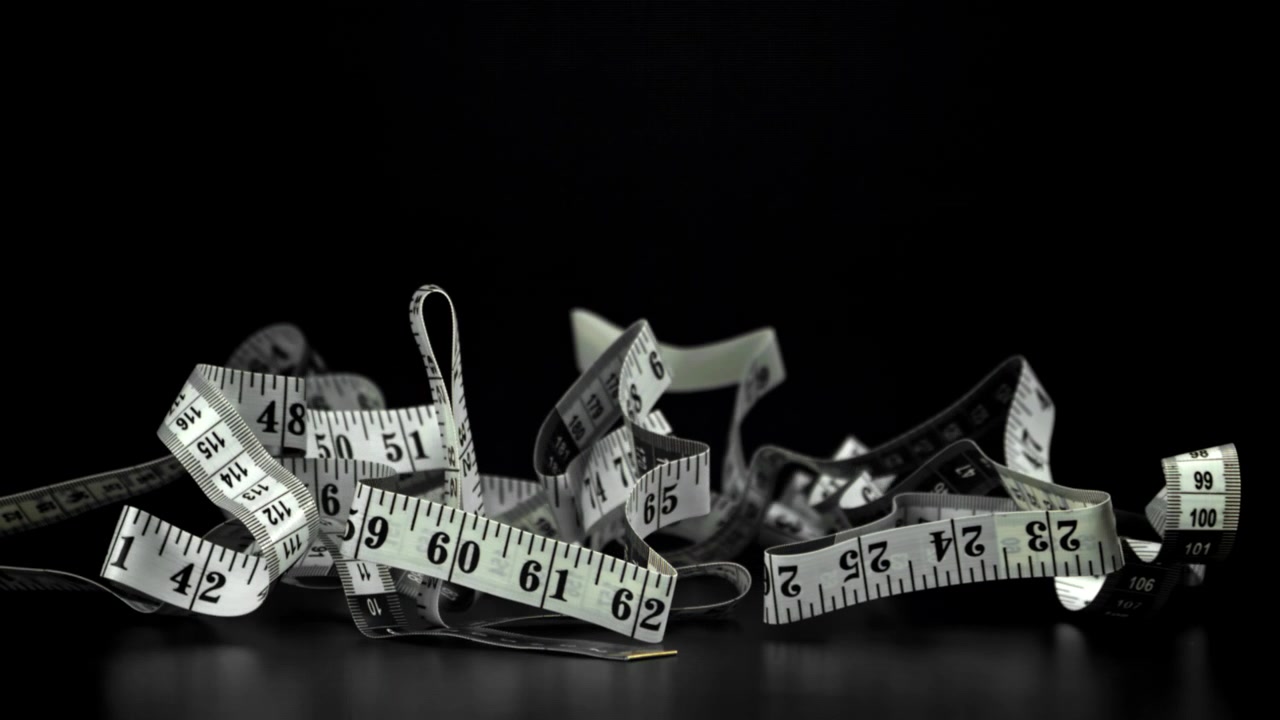 White Measuring Tape Falling onto Black Surface in Slow Motion
