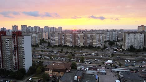 Vista-Aérea-De-Edificios-Antiguos-Y-El-Sistema-Ferroviario-De-Tranvías,-En-El-Distrito-Soviético-De-Troieshchyna,-Durante-La-Puesta-De-Sol,-En-Kiev,-Ucrania---Pan,-Drone-Shot