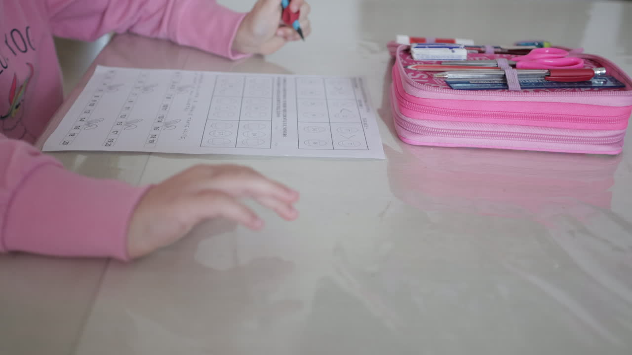 Child's hand writing homework in notebook