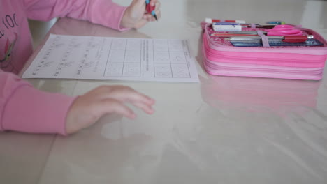 child's hand writing homework in notebook