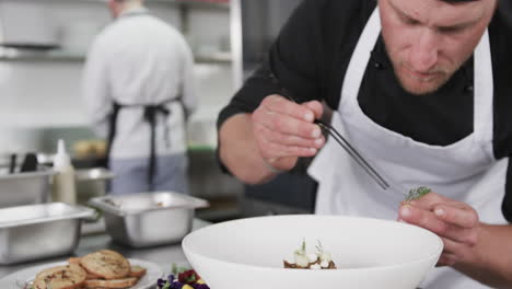 caucasian male chef decorating meal in kitchen, slow motion