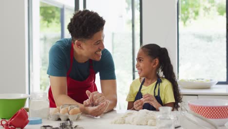 Happy-biracial-father-and-daughter-baking-together-in-kitchen