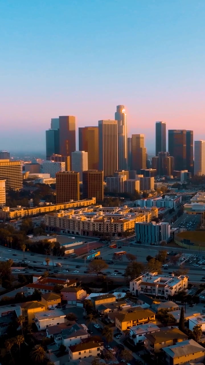 Veduta aerea del centro di Los Angeles al tramonto. I grattacieli dominano lo skyline. La congestione del traffico si verifica sulle strade urbane. Le palme sono visibili in primo piano