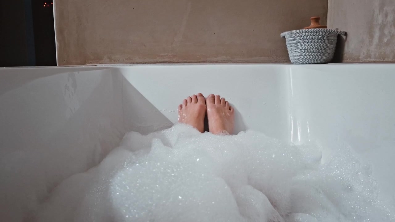 Feet and toes wiggle in a lovely and relaxing bubble bath tub at home