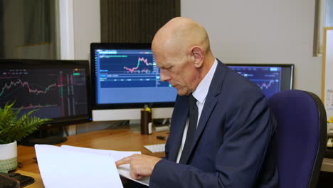 a mature business man reading a report in a trading office at his desk