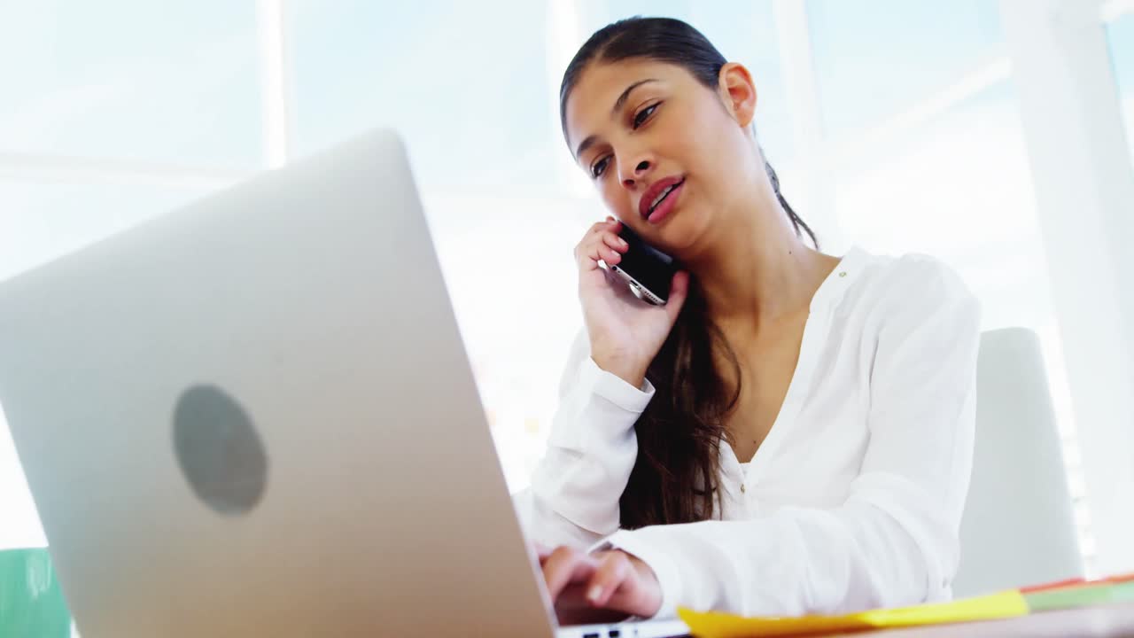 mujer llamando por teléfono inteligente y usando portátil
