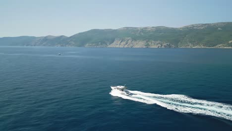 boat speeding through clear blue sea near rugged coastline, aerial view