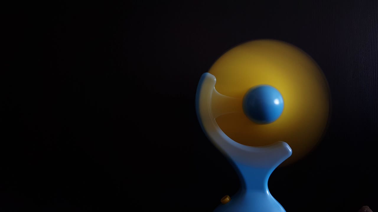 검은 바탕에 회전하는 파란색과 노란색의 미니 전기 팬