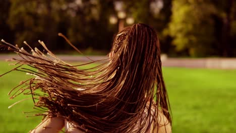 Long-hair-woman-with-dreads-running-in-park-and-turning-around-looking-in-camera.-Back-of-running-woman-in-slow-motion