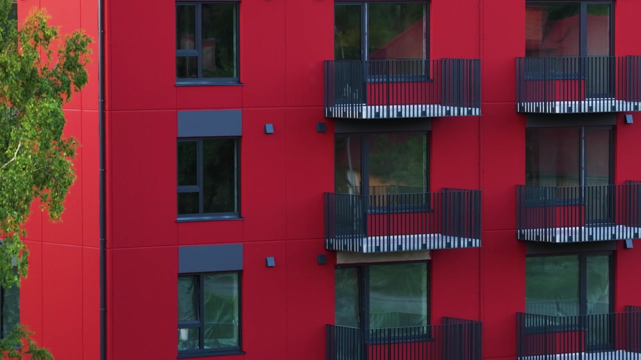 Fachada roja de edificio de apartamentos moderno con balcones en una obra de construcción