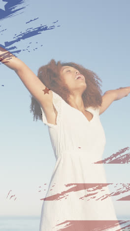 animation of american flag over african american woman raising hands at beach