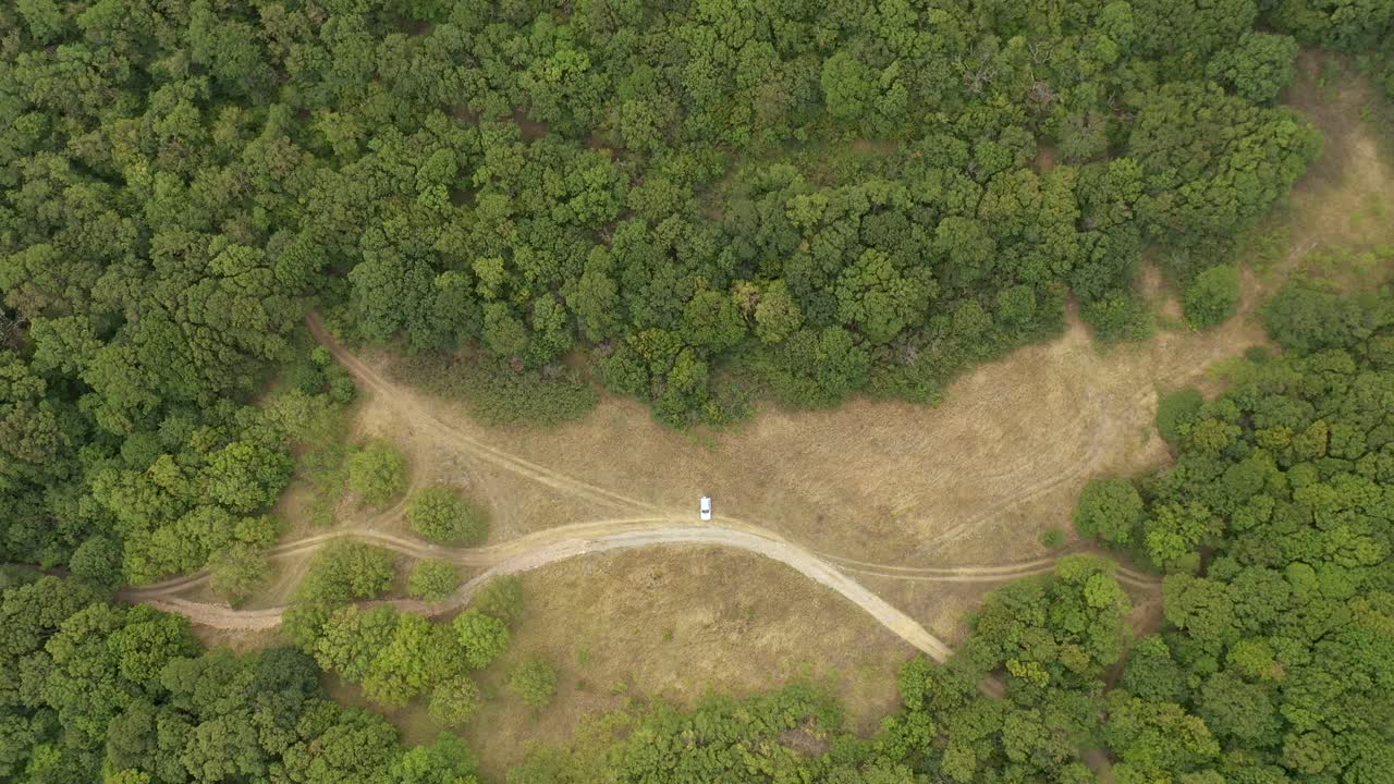 조지아 므츠헤타 근처에서 여름까지 중앙에 흰색 차가 주차되어 있는 위에서 내려다보는 숲의 질감