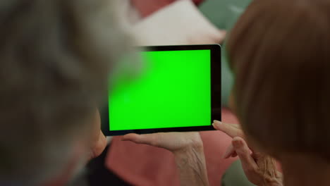 Blick-Von-Oben-Auf-Die-Hände-Einer-älteren-Frau-Und-Eines-Mannes,-Die-Ein-Digitales-Tablet-Mit-Grünem-Bildschirm-Verwenden