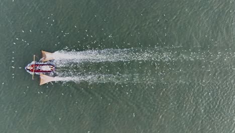 Drone topdown shot of a Fishers boat dragging the nets thru the water