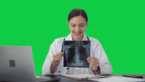 una mujer india feliz chequeando el informe de rayos x pantalla verde