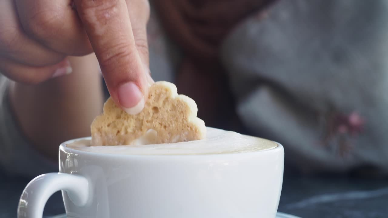 커피 한 잔 에 쿠키 를 담그고 있는 여자