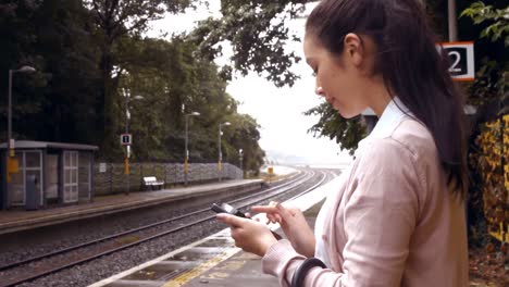 mujer de negocios usando el teléfono en la plataforma del tren