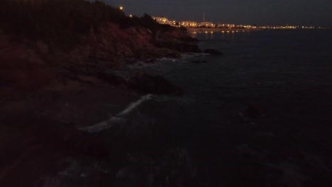 Drone-casually-flying-near-cliff-at-the-beach-during-sunset