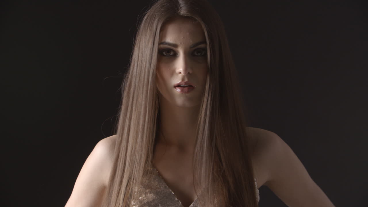 una mujer joven camina hacia la cámara, se enfoca, mueve el cabello, sonríe.