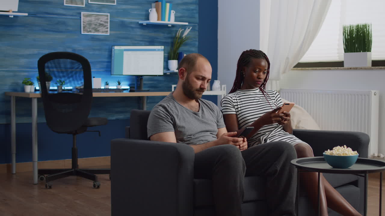 Interracial people using smartphones while sitting together
