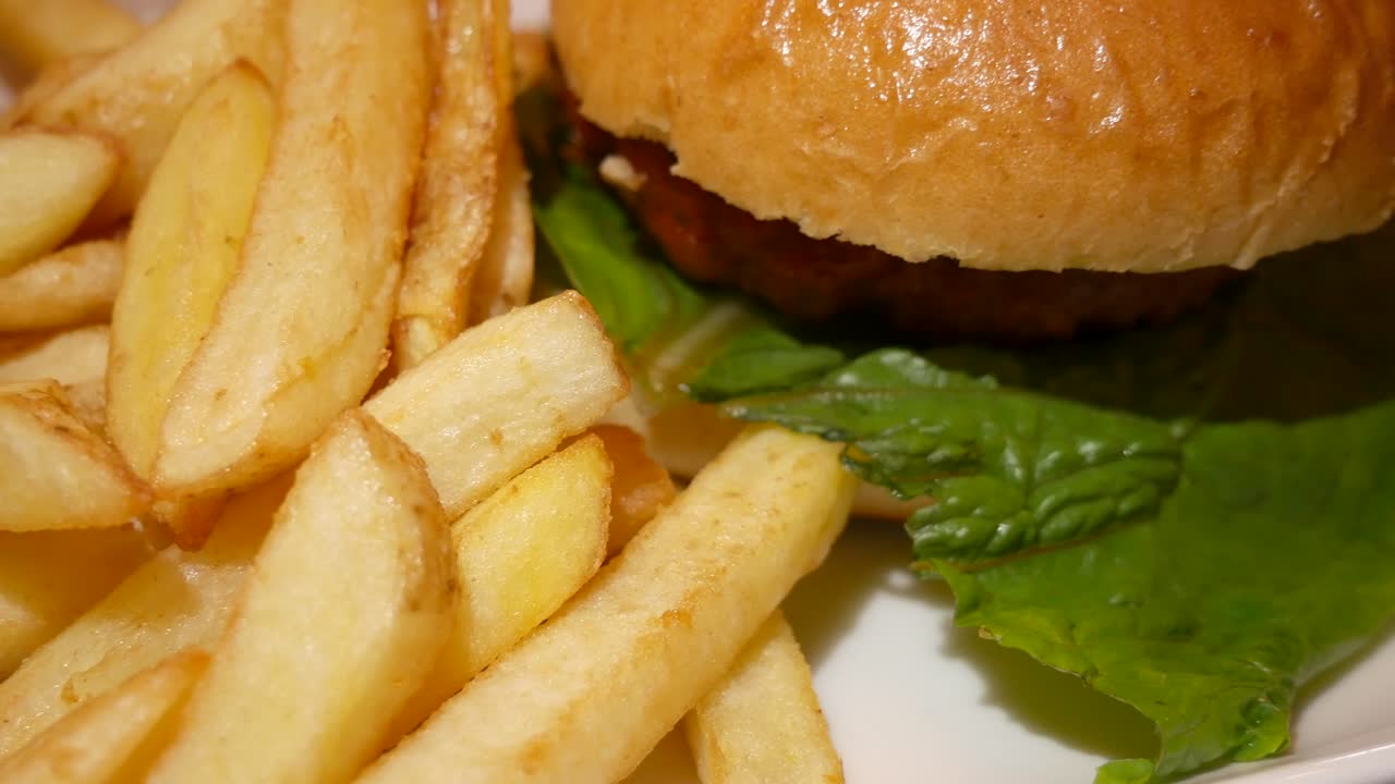 hamburguesa en pan brioche con papas fritas en un plato blanco
