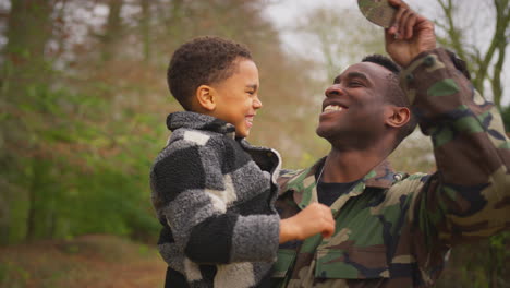 close up of american soldier returning home to family on leave carrying son wearing army cap