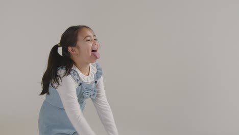 retrato de estudio de una chica hiperactiva sonriendo y sacando la lengua contra un fondo blanco