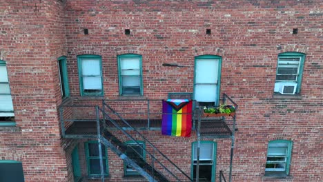 orgullo gay y bandera aliada transgénero en la escalera de incendios de un antiguo edificio de apartamentos de ladrillo en el centro de la ciudad