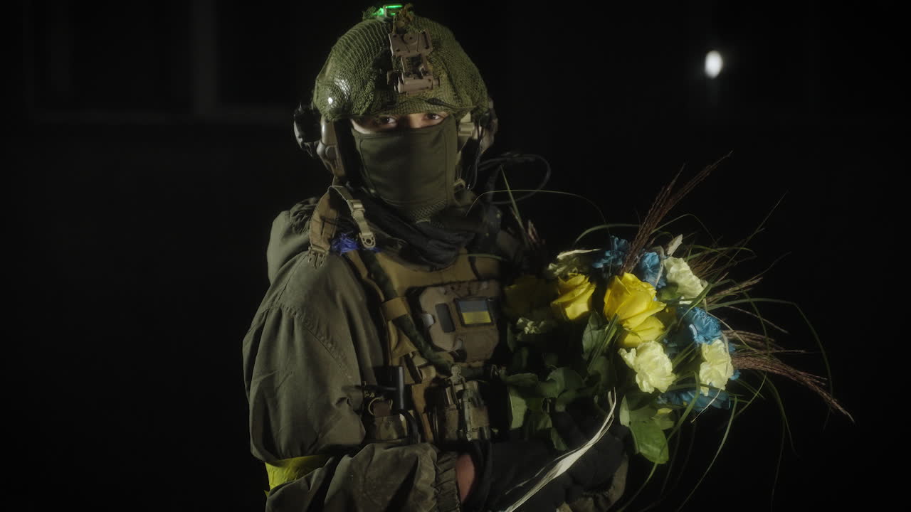 Ukrainian soldier holding flowers at night