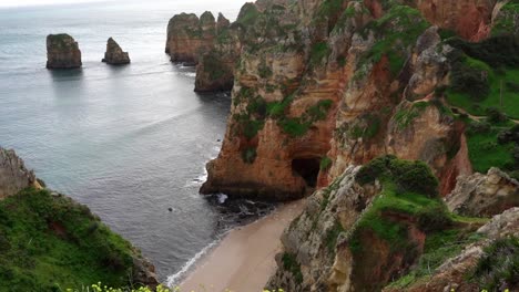 La-Cámara-Se-Inclina-Hacia-Arriba-Y-Revela-Los-Magníficos-Acantilados-De-Arenisca-Roja-Y-Las-Imponentes-Formaciones-Rocosas-A-Lo-Largo-De-La-Costa-Del-Algarve-En-La-Región-De-Lagos,-En-El-Sur-De-Portugal.