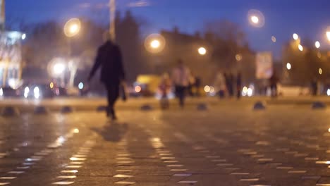 cinematic bokeh with evening city street and people in the light of headlights and lanterns