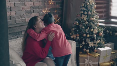 Una-Mujer-Bastante-Joven-Abraza-A-Niños-Pequeños-Cerca-Del-árbol-De-Navidad