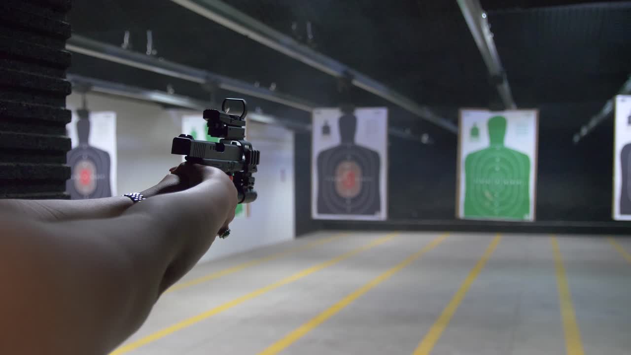 Shooting range practice. Woman shooting with tactical handgun at indoor targets.