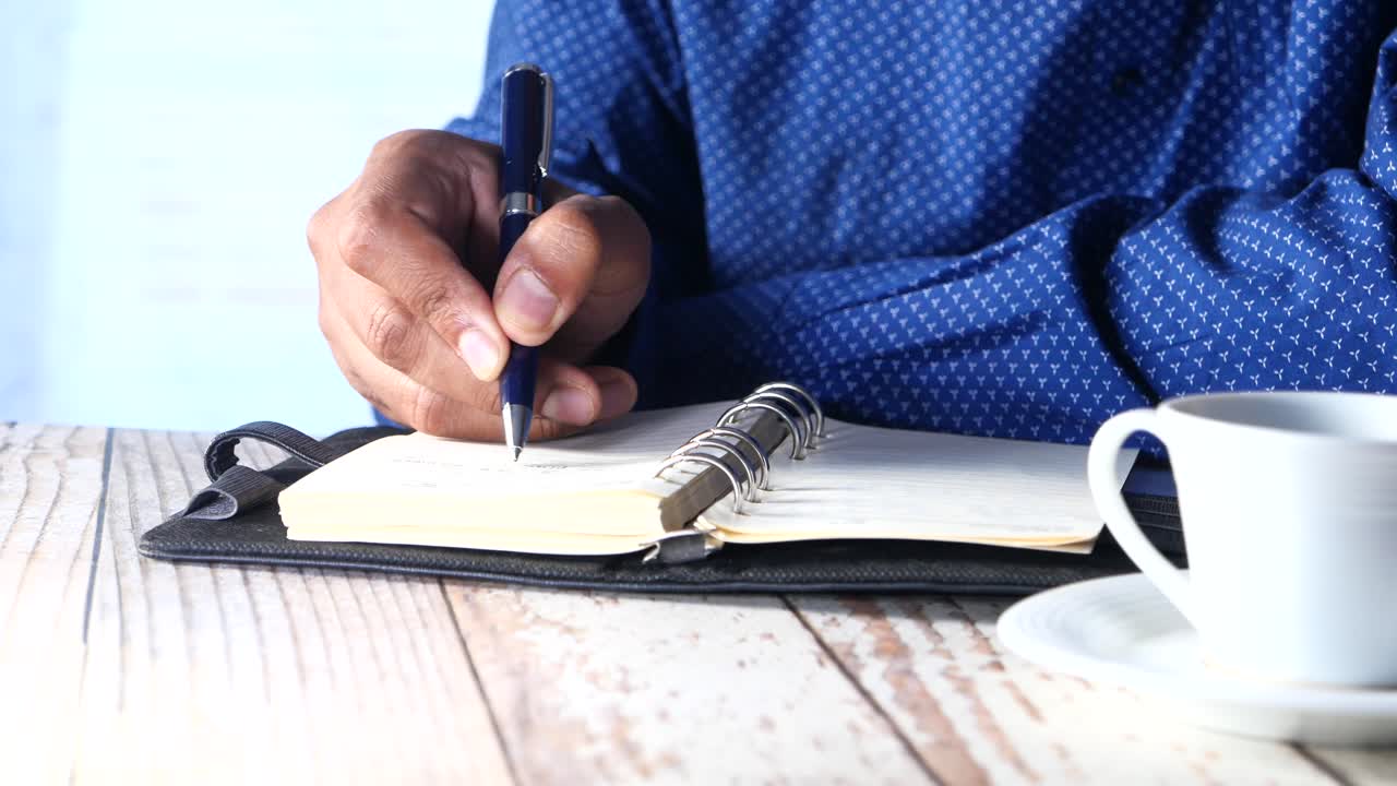 Person Writing in a Notebook with Coffee