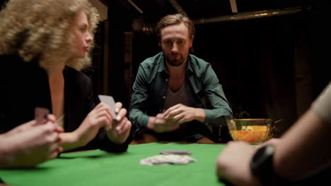 group of friends playing poker sitting on chairs at a table at home 7