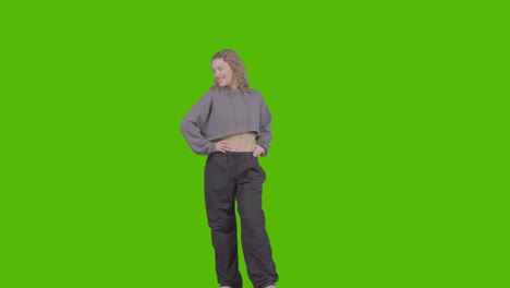 full length studio portrait of smiling young woman against green screen