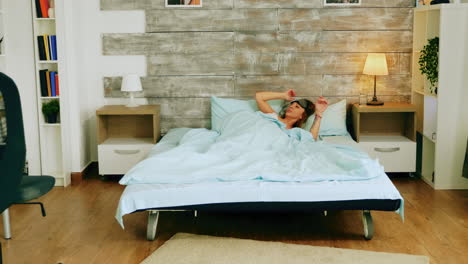 una mujer joven se despierta por la mañana con una máscara para dormir.