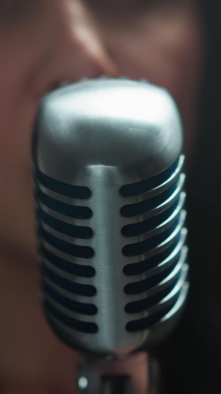 Close-up of a vocalist with blurred focus, singing into a vintage microphone against a soft, blurred background with dynamic camera movement