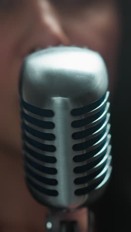 primer plano de un vocalista con enfoque borroso, cantando en un micrófono vintage contra un fondo suave y borroso con movimiento dinámico de la cámara