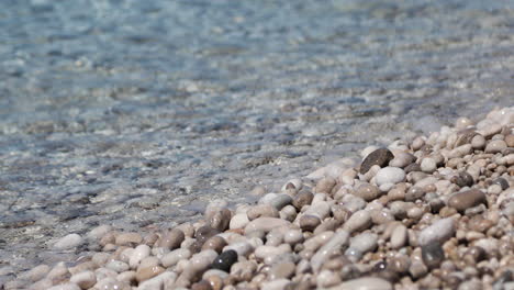 clean sea water of mediterranean sea rolling in sunshine to the pebbles beach