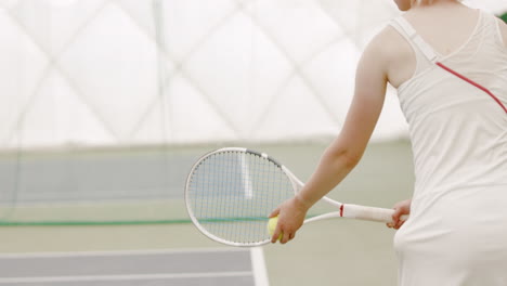 MED-SIDE-VIEW-Young-Caucasian-female-tennis-player-serving-during-a-game-or-practice.-120-FPS-slow-motion,-4K-UHD-RAW-graded-footage