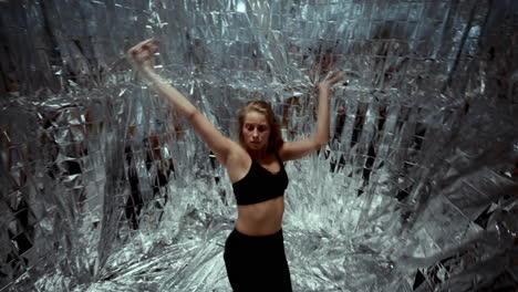 young woman dancing modern choreography in foil-covered studio