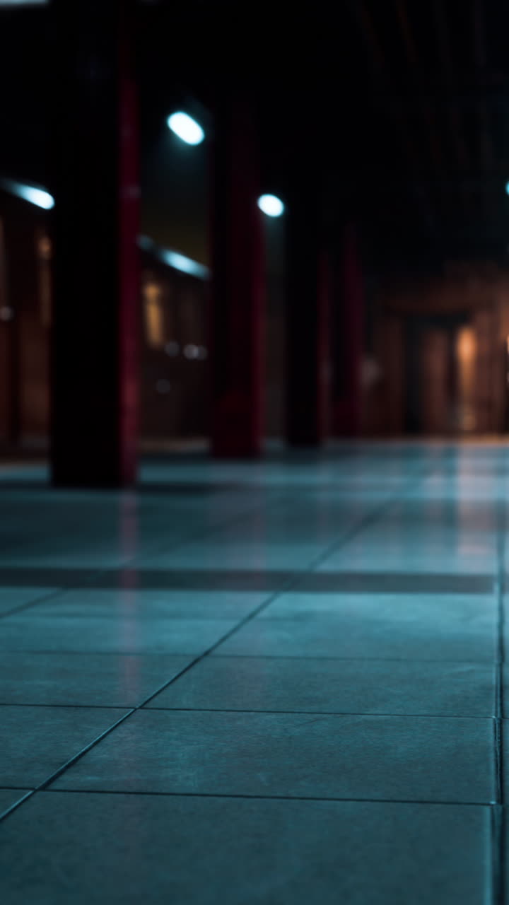 un pasillo largo y vacío con pilares rojos y un piso de azulejos