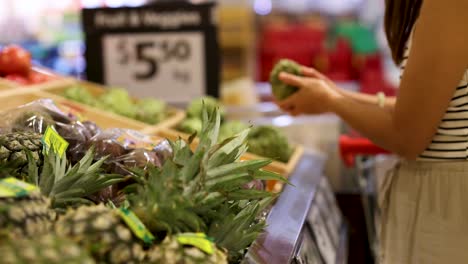 a person examines and selects fresh fruit in a well-lit gold coast supermarket, focusing on quality and choice