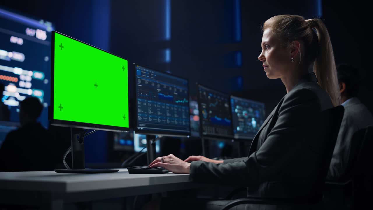 científica de datos femenina confiada trabaja en una pantalla clave de croma verde en una gran sala de control de infraestructura. los especialistas usan computadoras que muestran gráficos, información. equipo profesional de la sala de control