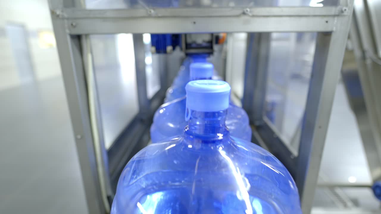 una vista de cerca de una línea automatizada de embotellado de agua, que muestra el proceso eficiente e higiénico de llenar grandes botellas de agua en una instalación industrial de producción de agua